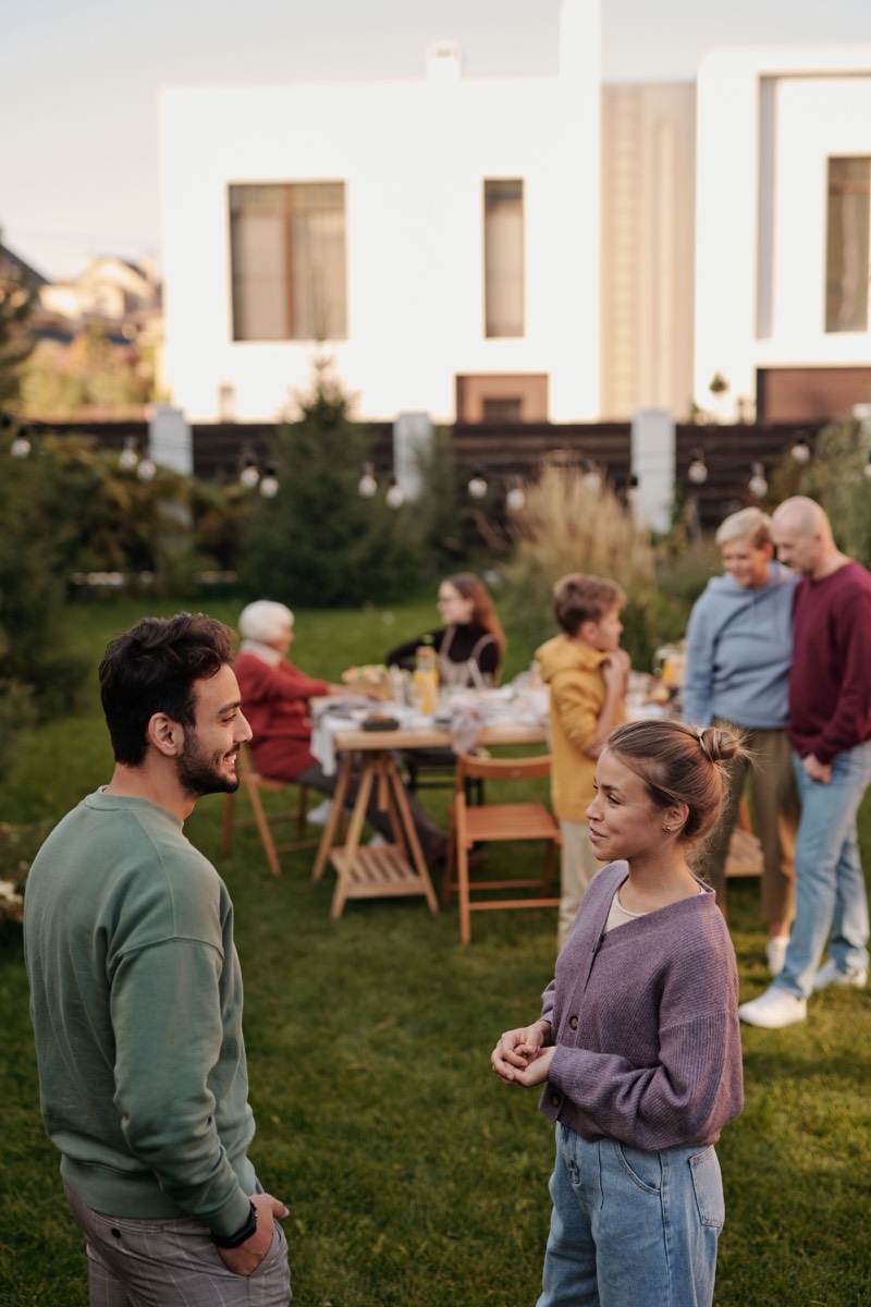 People of different ages sitting together around a table in a garden.